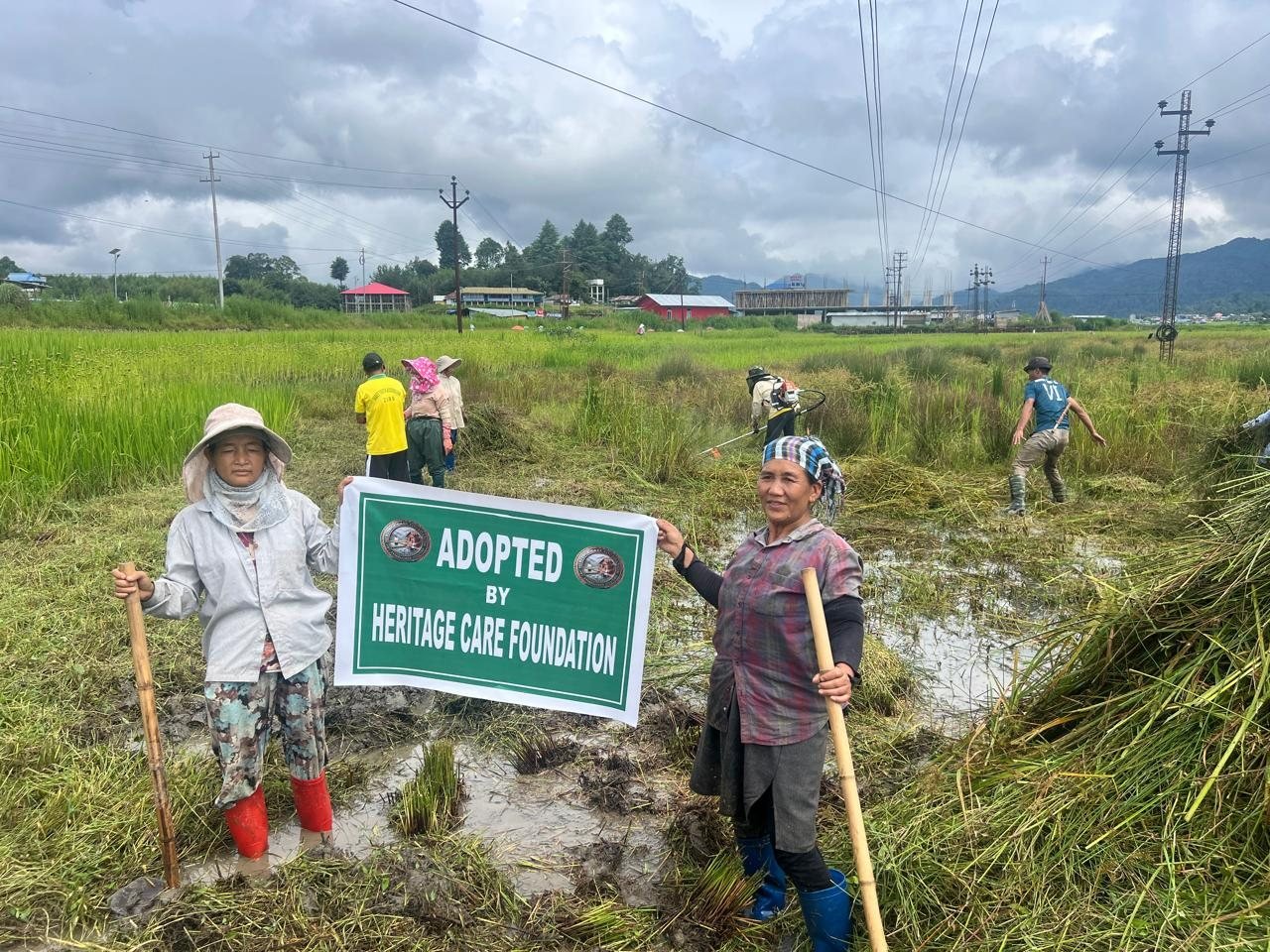 Volunteers holding the “Adopted by Heritage Care Foundation” sign in a field